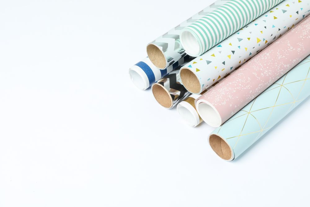 Rolls of festive wrapping paper on light background. Space for text