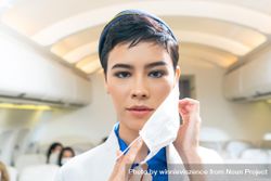Flight attendant taking off facemask in airplane 4Zl2O0
