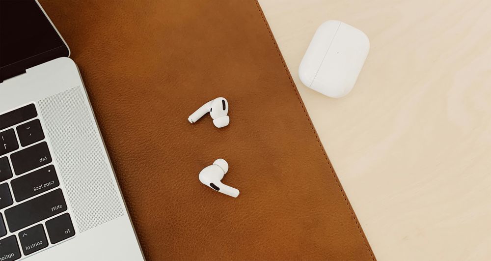 Wireless Earbuds on Laptop and Two-Tone Desk