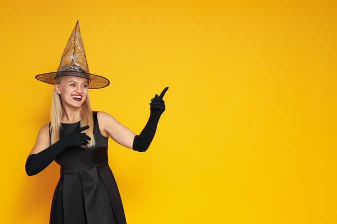 Concept of Halloween, young woman on yellow background
