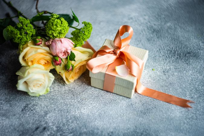 Pastel flowers on grey counter with gift wrapped in ribbon