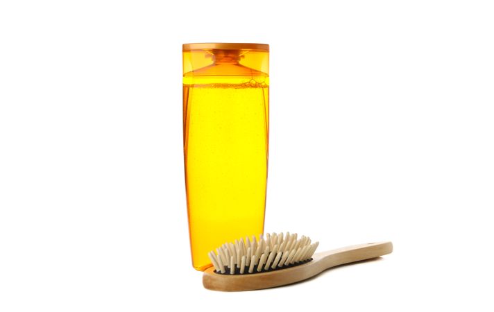 Blank shampoo bottle and hair brush isolated on light background