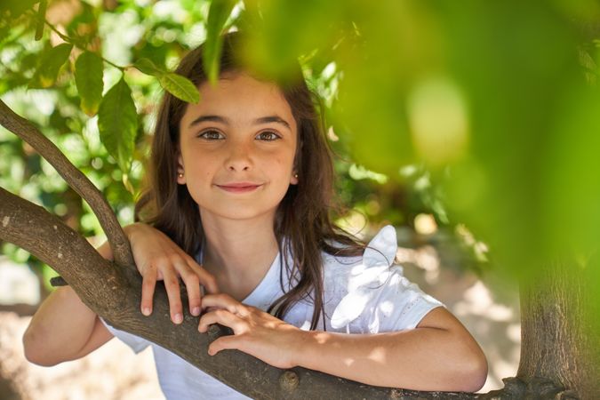 Satisfied kid leaning on branch in green forest