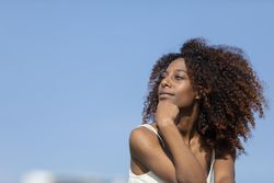 Female with curly hair in deep thought outside