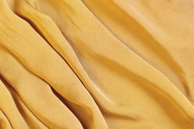 Top view of ochre colored silk fabric shaped in waves