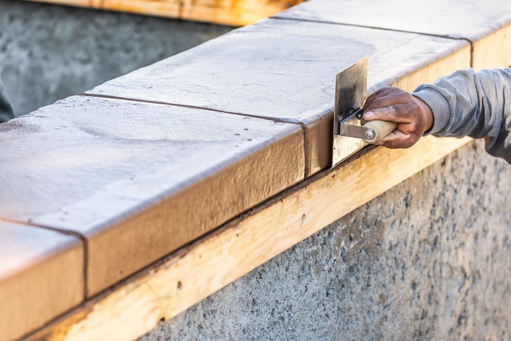 Construction Worker Using Stainless Steel Edger On Wet Cement Forming Coping Around New Pool