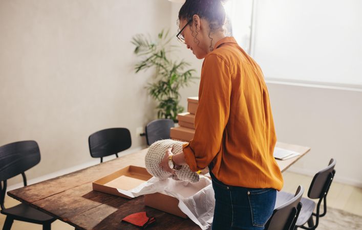 Woman working at home office packaging a delivery box