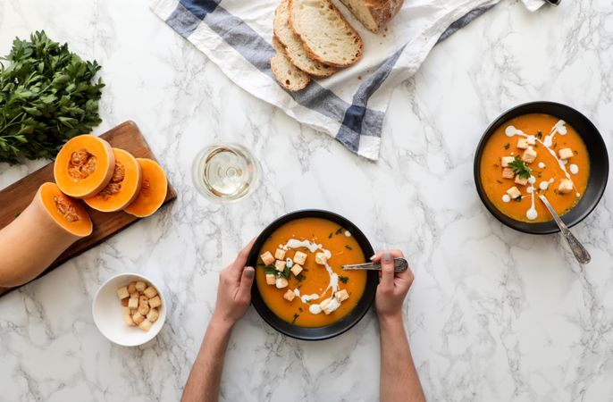 Person hands holding bowl with carrot soup