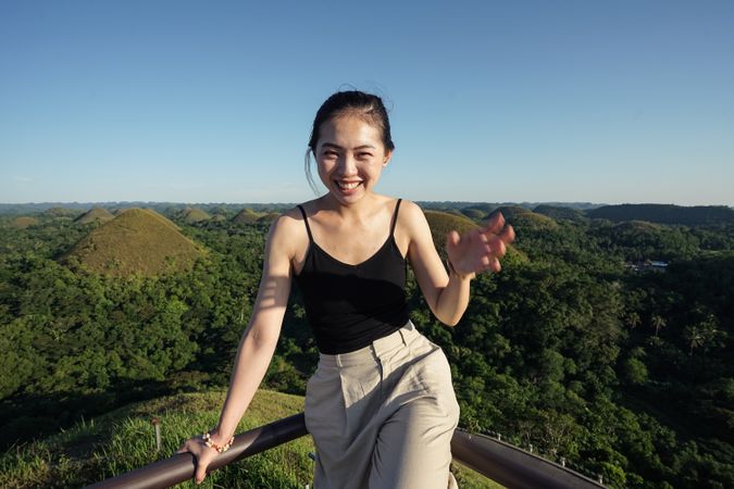 Happy woman standing on observation deck on hill