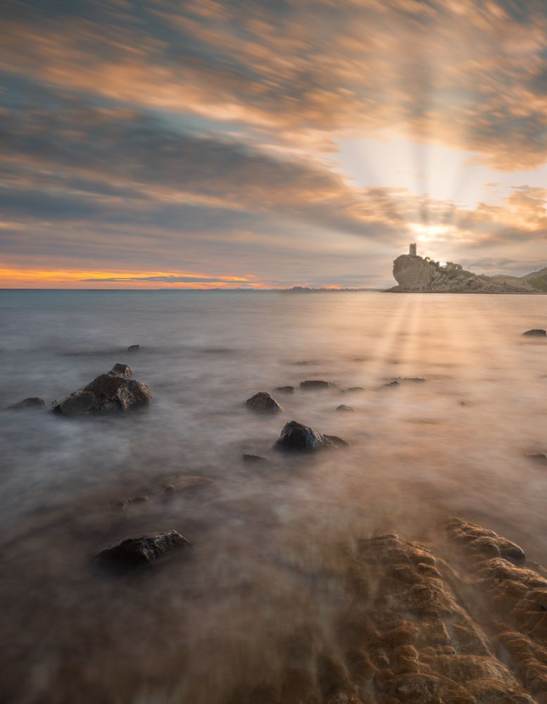 Sundown sky over sea and stony coast