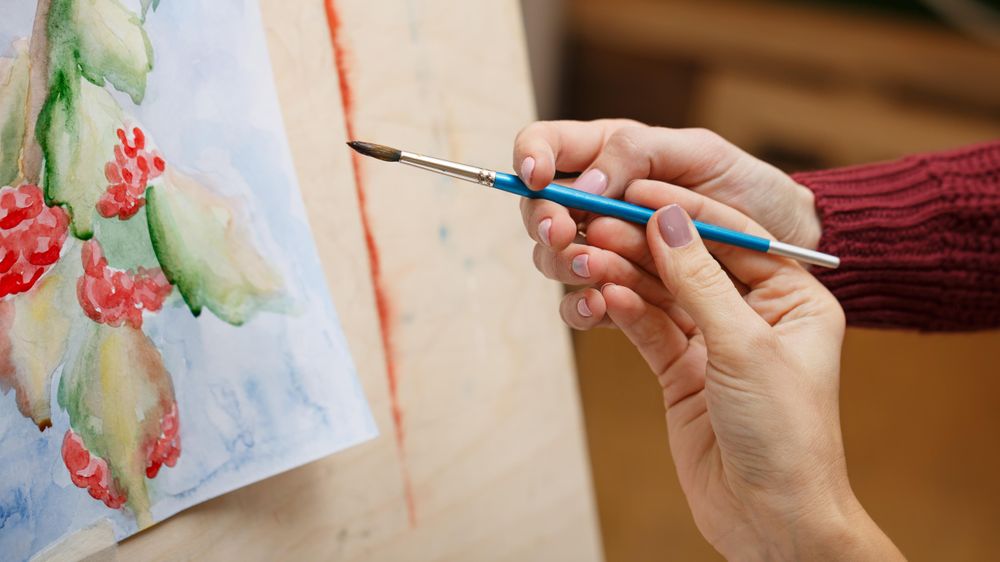 Teacher showing student how to hold a paintbrush