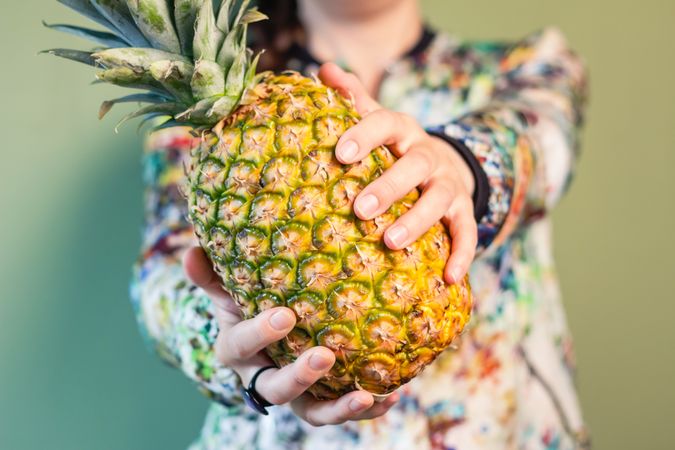 Woman holding pineapple between her hands