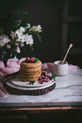 Pile of raspberry pancakes with honey on plate