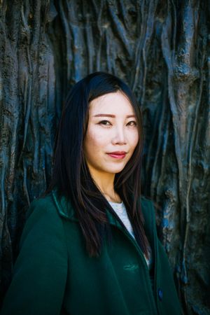 Pensive Asian woman leaning on rough wall