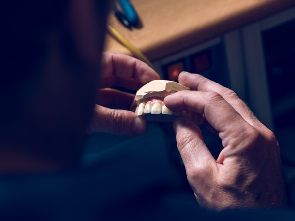 Crop man examining artificial denture