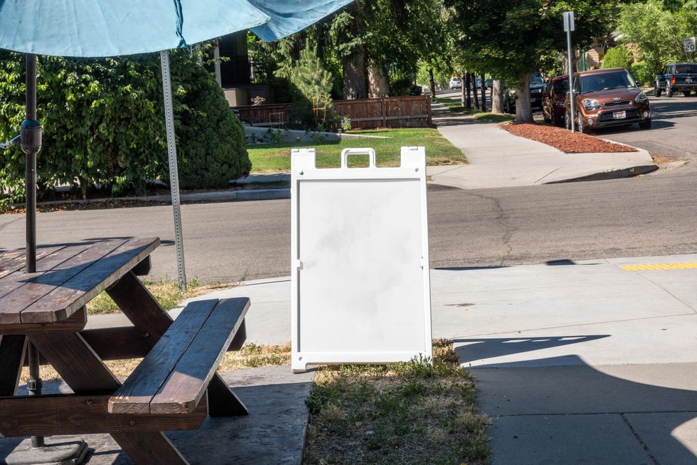 Plastic a-frame mockup outside restaurant picnic table seating