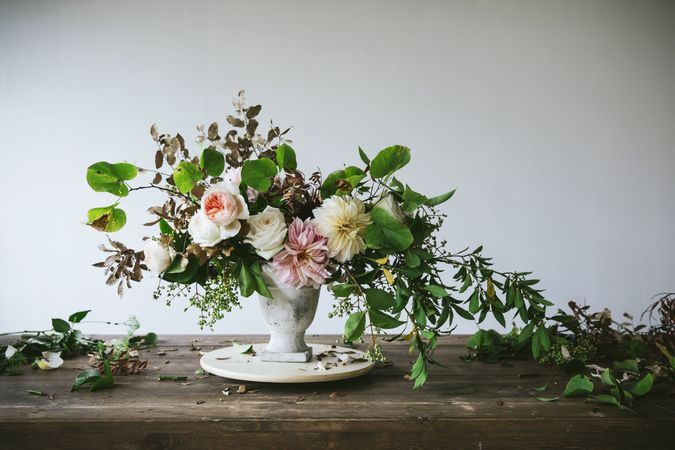 Composition of flowers and plants in vintage vase on board