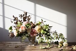 Composition of flowers and plants in vintage vase on board