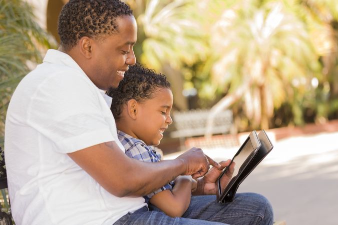 Father And Son Using Touch Pad Computer Tablet Outside
