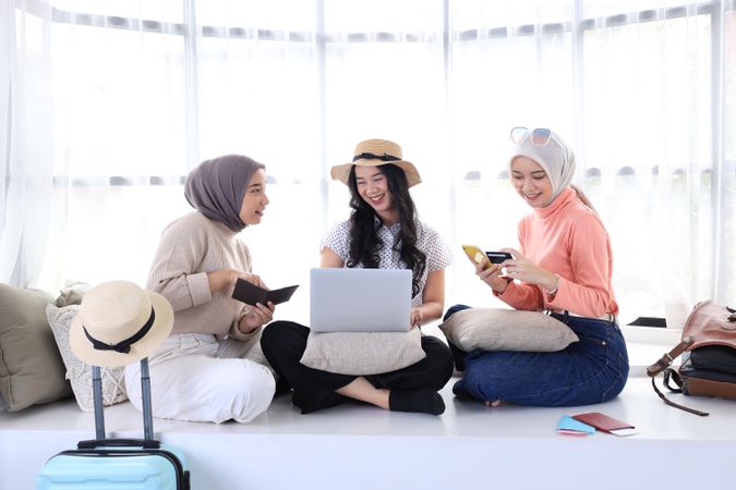 Three Asian female Best Friends Booking Tickets for Vacation  using Laptop and Credit Card