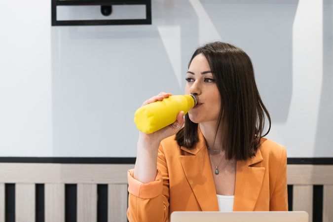 Woman drinking water during work in cafe