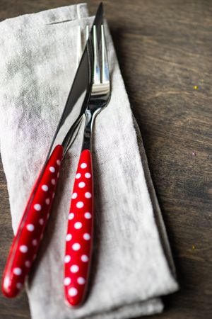 Red dotted cutlery on napkin on wooden table