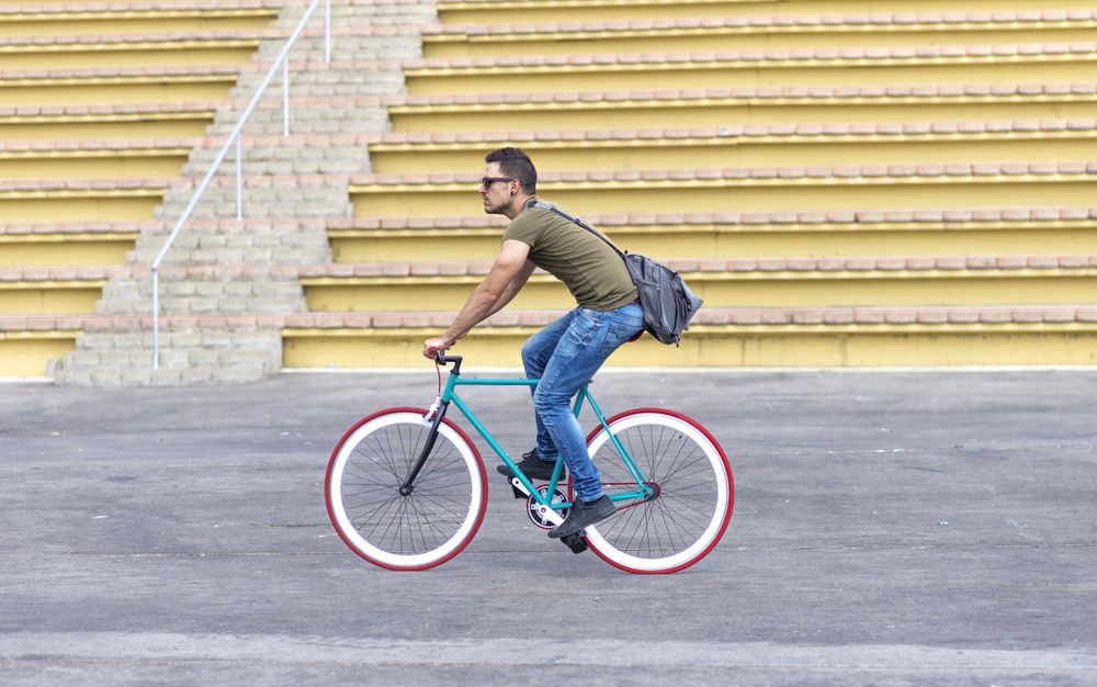 Male on bicycle with outdoor seating in background