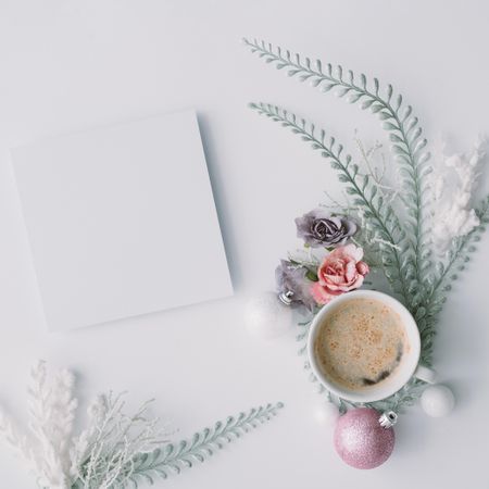 Coffee and paper card with flowers, leaves and pink Christmas decoration