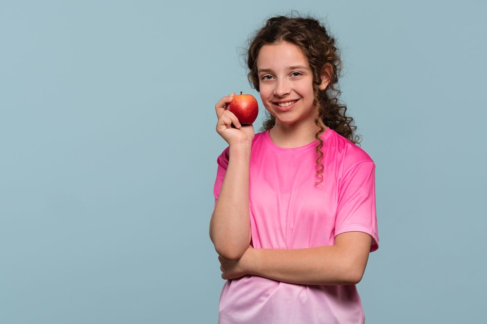 Smiling young girl holding red apple