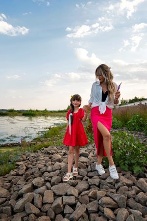 Mom and little daughter walking by the lake or pond