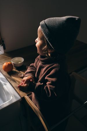 Adorable calm little boy standing near table in kitchen in sunli