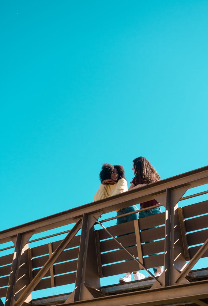 Two friends talking on a bridge.