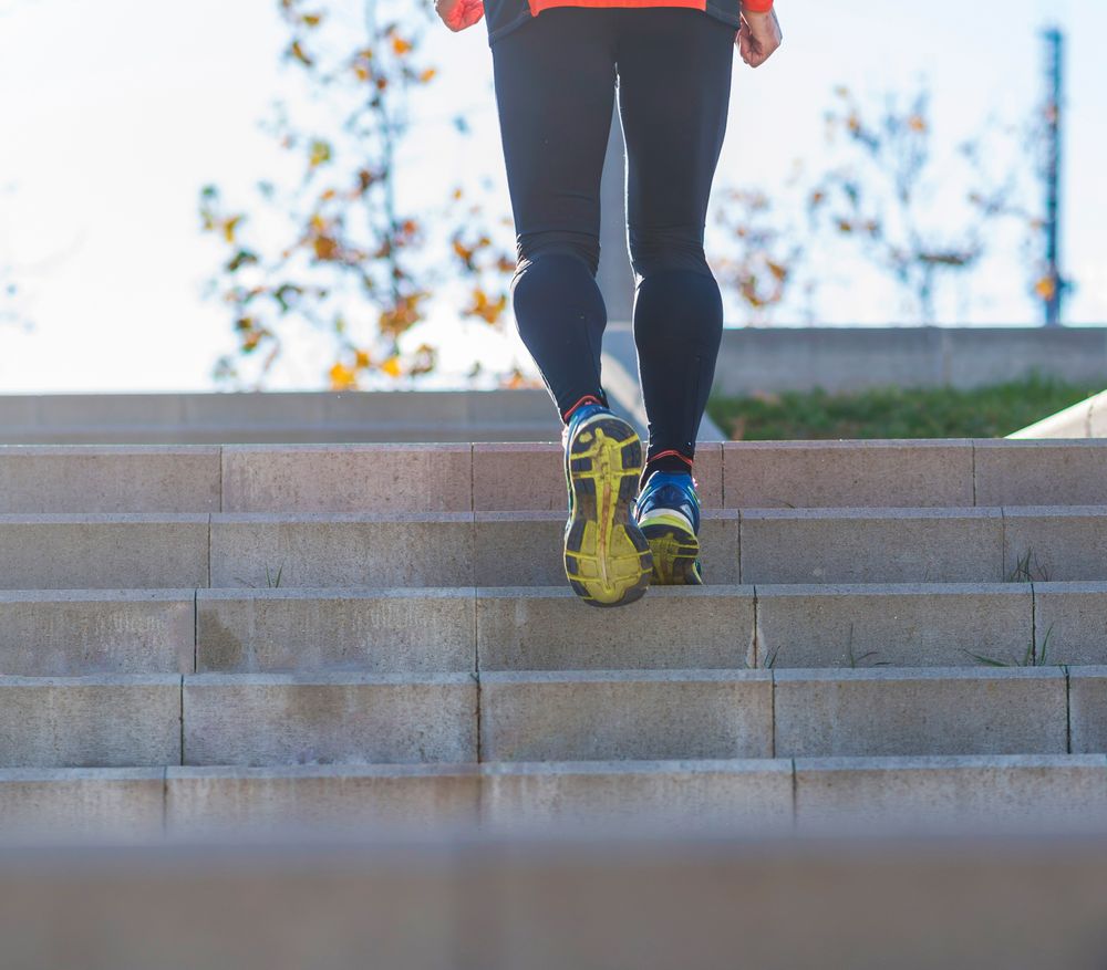 Feet of person walking up cement stairs