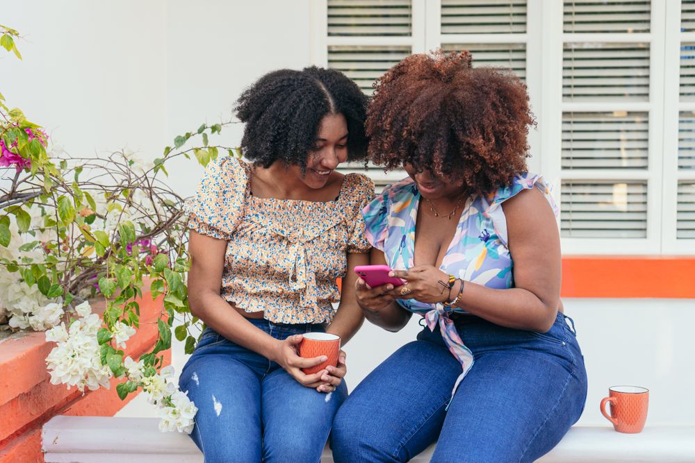 Two Black friends using their cell phones