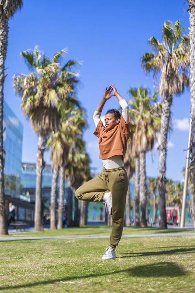 Black female balancing under the palms in a promenade