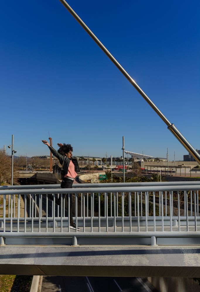 Woman with afro hair jumping for joy in the streets.
