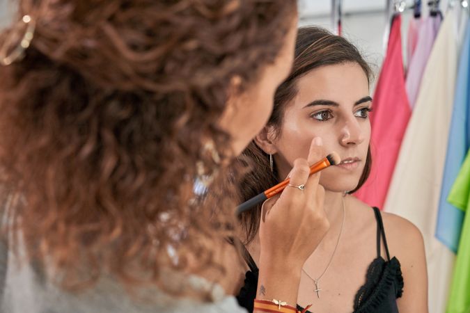 Unrecognizable woman applying powder on model