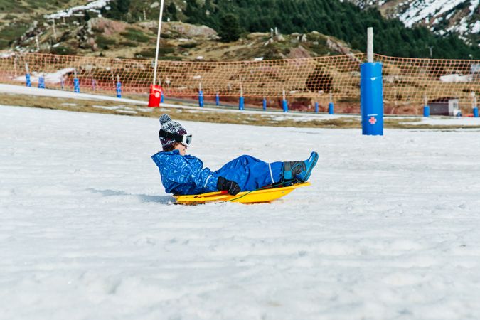 Boy sliding on snow on ski resort