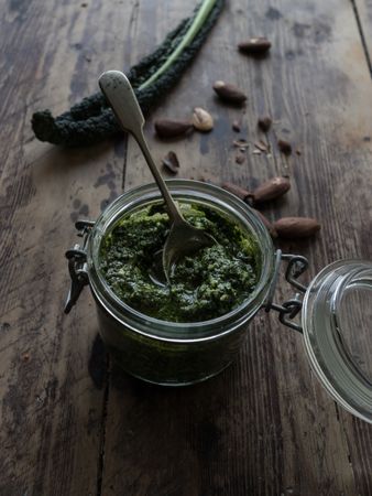 Jar with kale pesto near nuts