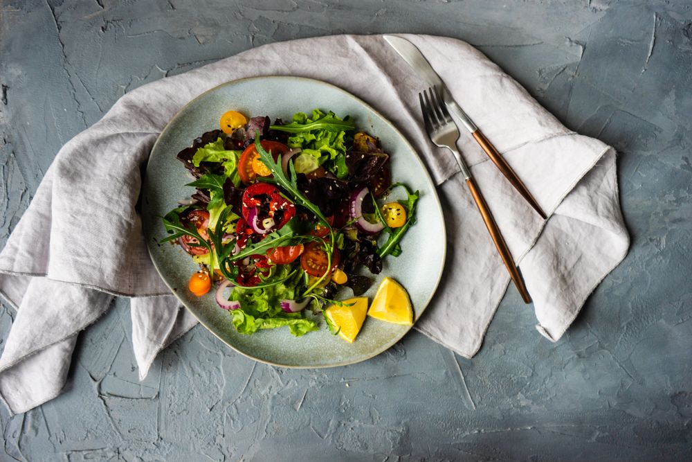 Organic vegetable salad on counter with napkin and cutlery