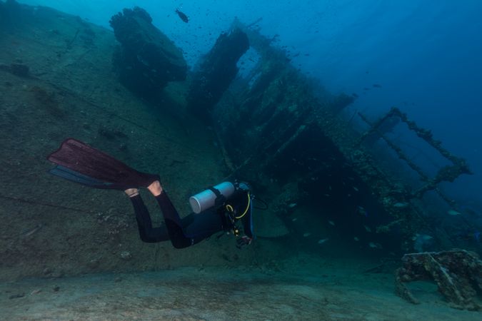 Scuba divers swimming underwater exploring wreckage