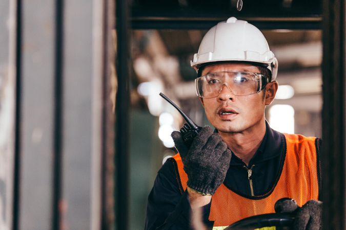 Asian male warehouse worker talking walkie-talkie