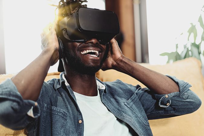 Black man with VR googles smiling reacting to metaverse experience