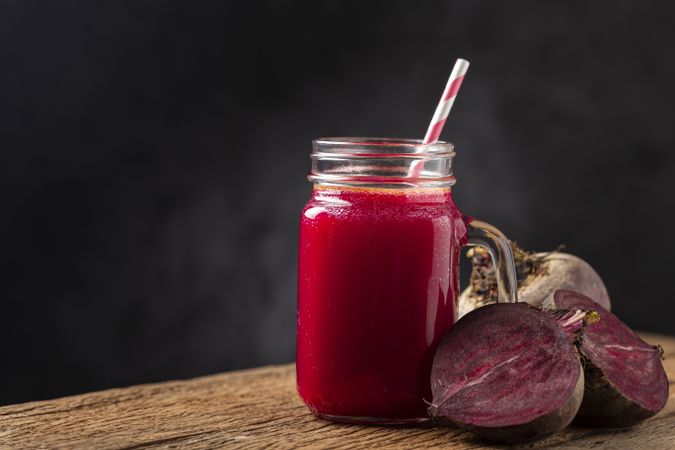 Red beet juice in a glass cup on the wooden table.