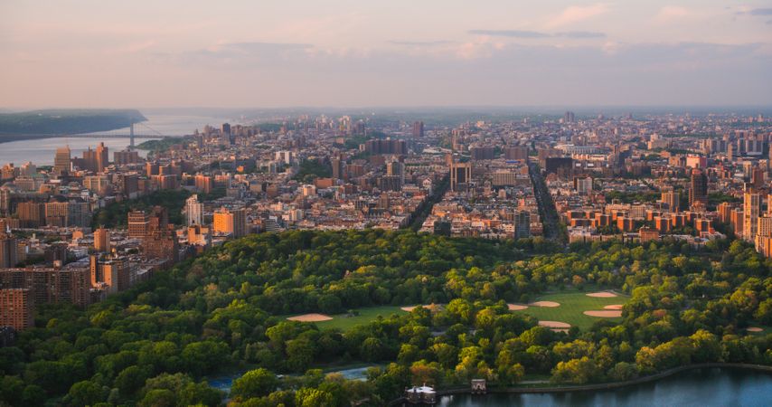 New York Cityscape at Sunset. Aerial Shot from a Helicopter. Modern Skyscraper Buildings Around Central Park in Manhattan Island. Focus on Nature, Trees and Lakes in the Park in the City