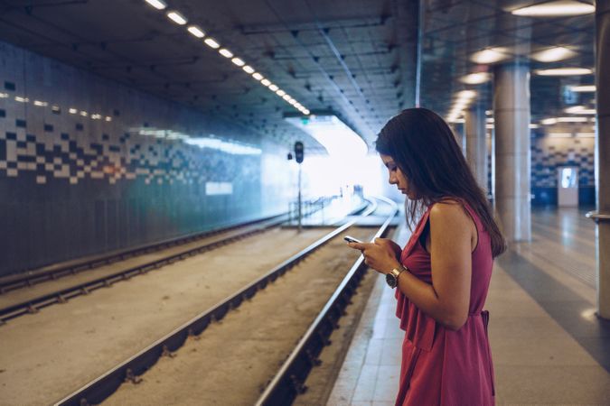 Long haired woman with smartphone standing in front of subway car