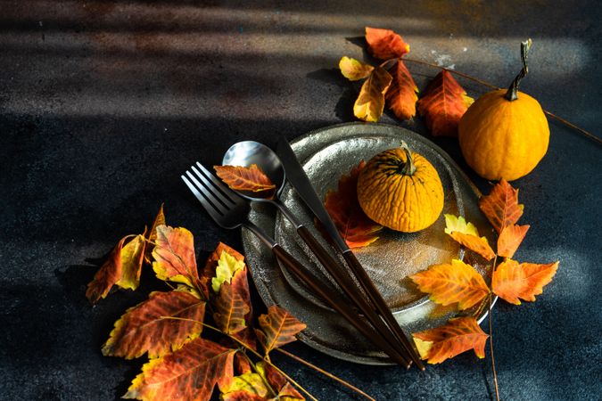 Autumn table settings of shiny ceramic plates with leaves and cutlery