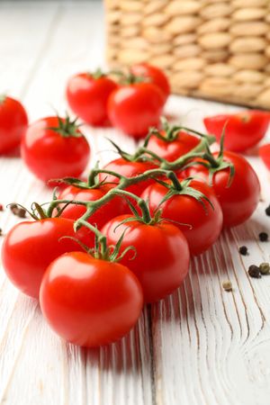 Tomatoes, pepper and basket on wooden background, close up