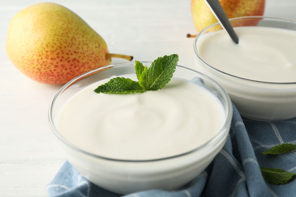 Cream yogurt, pears, towel and mint on wooden background, closeup