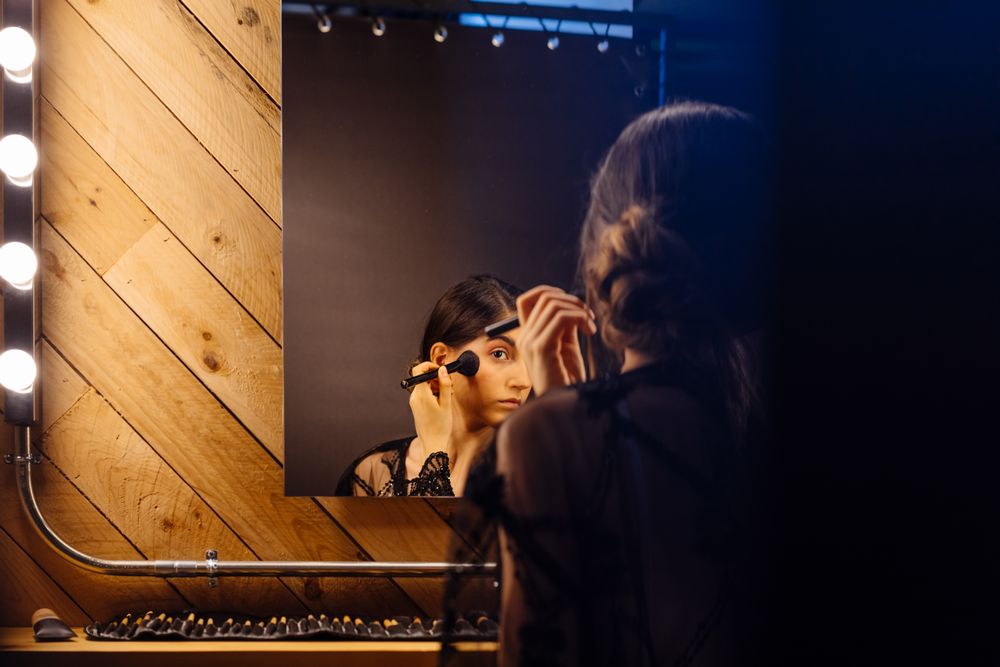 Beautiful brunette female in peignoir applying makeup